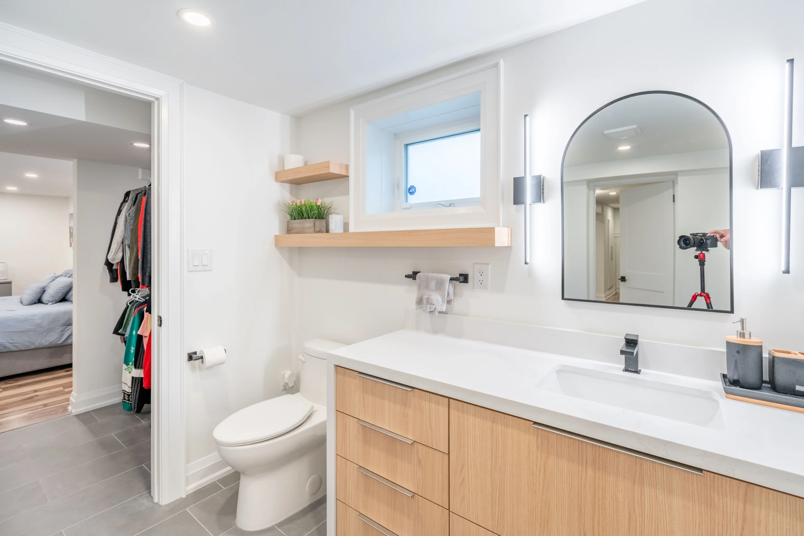 Photo of modern bathroom with wood vanity toilet window shelves and bedroom access showing what is a jack and jill bathroom