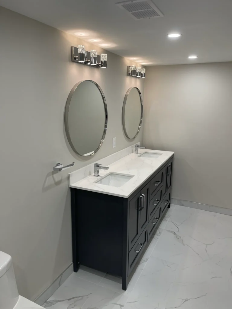 Photo of modern double vanity bathroom with two round mirrors and white countertop illustrating what is a jack and jill bathroom layout
