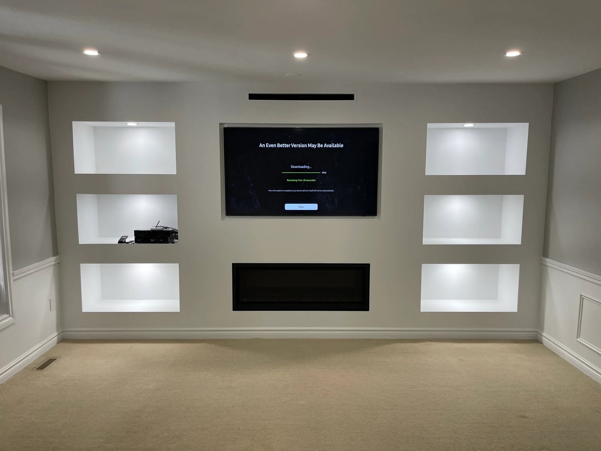 photo basement media wall with mounted tv fireplace and lit built in shelves on both sides