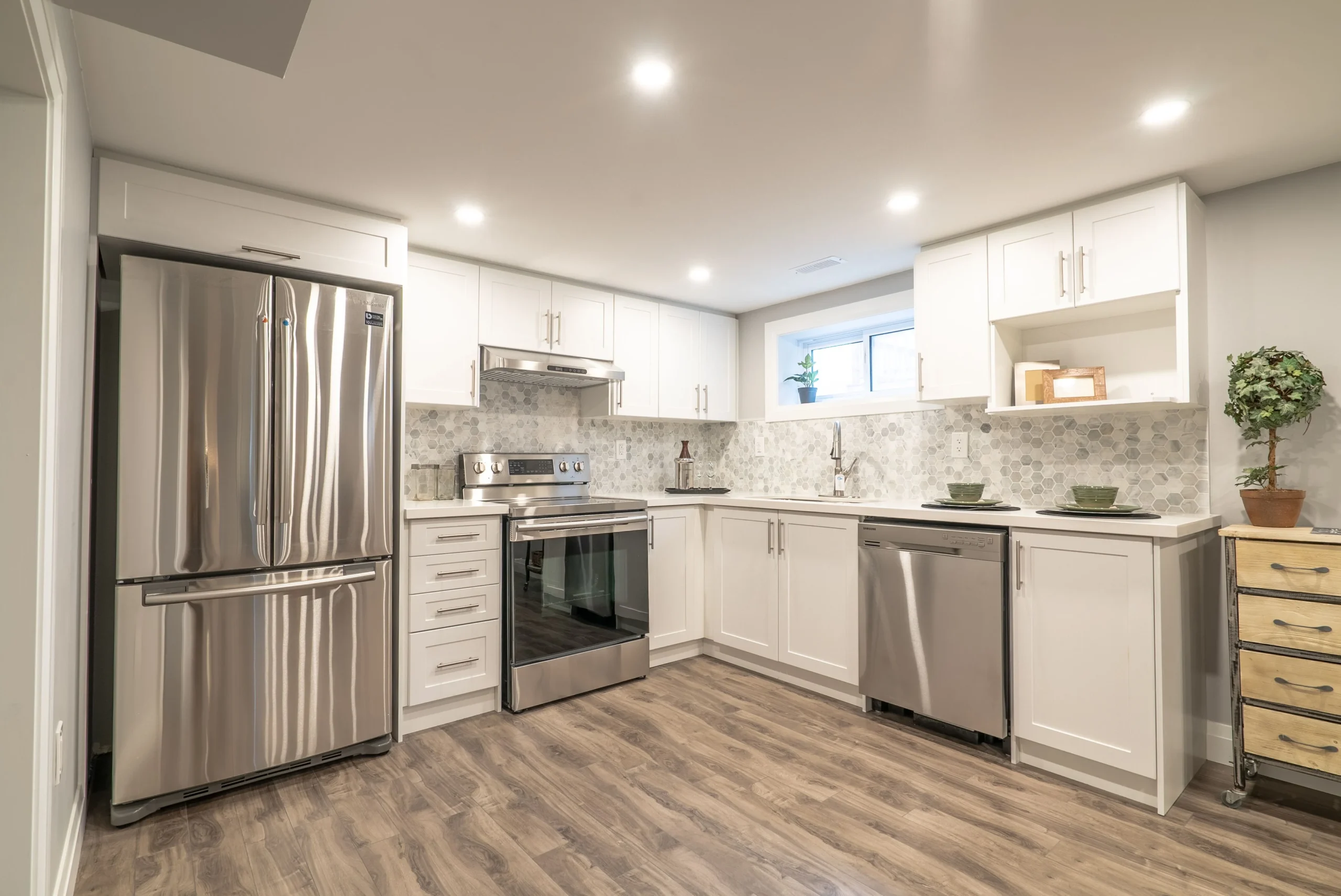 photo modern kitchen with white cabinets stainless steel appliances hexagon backsplash window and wood flooring