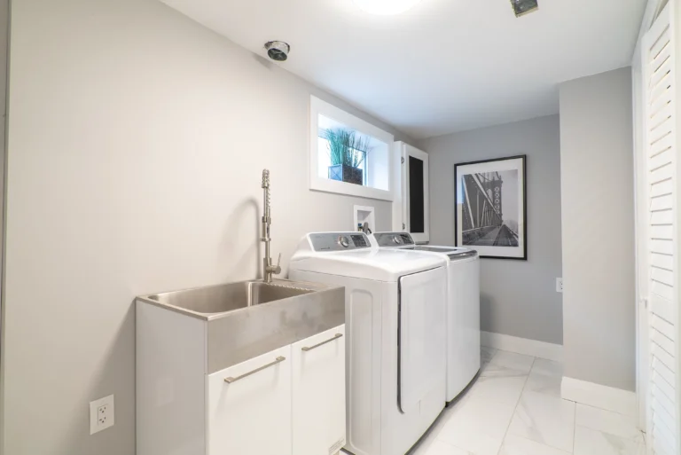 photo-of-laundry-room-with-washer-dryer-utility-sink-small-window-and-framed-bridge-wall-art