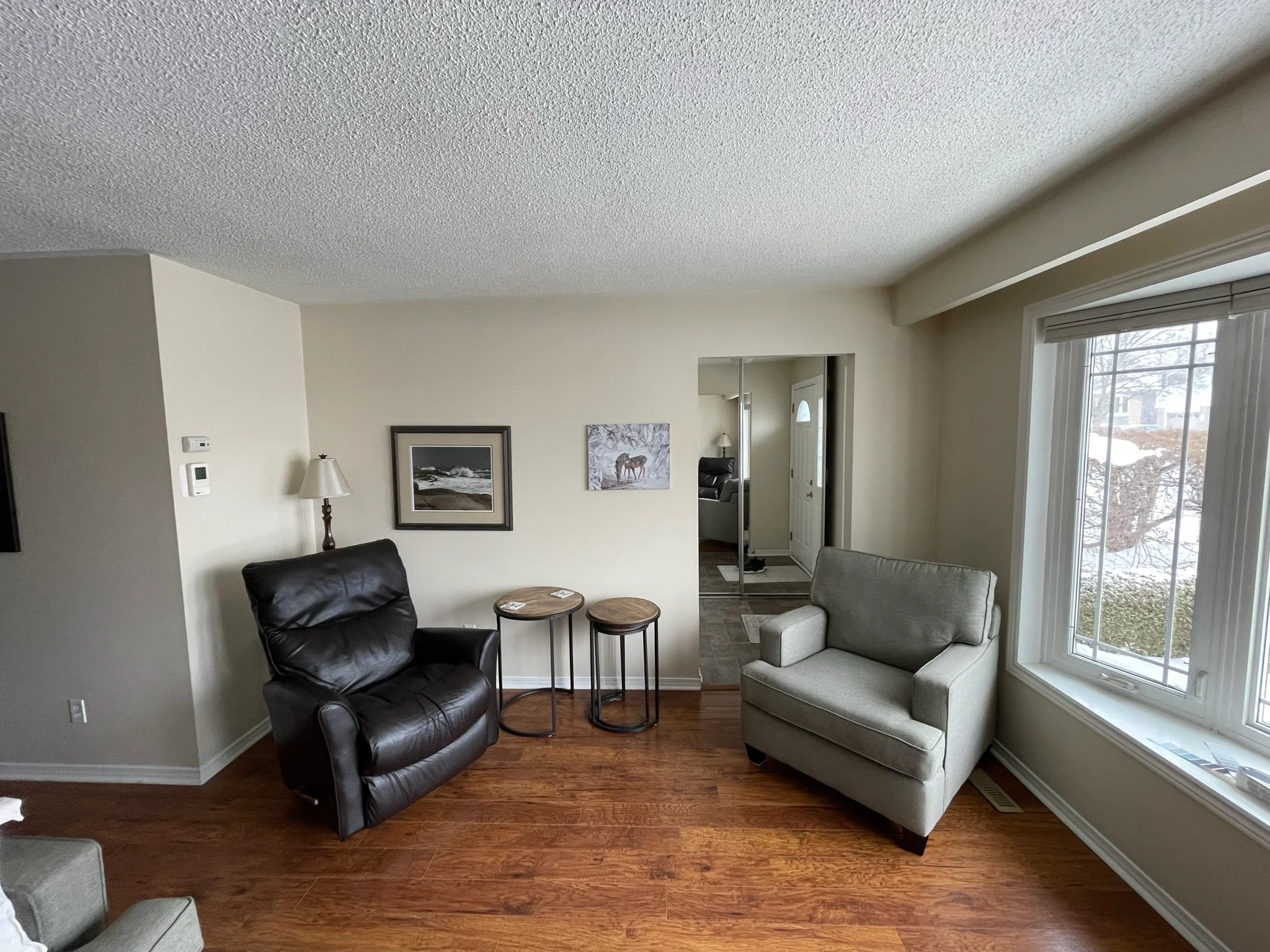 photo-of-living-room-with-two-armchairs-side-tables-wall-art-large-window-and-wood-flooring