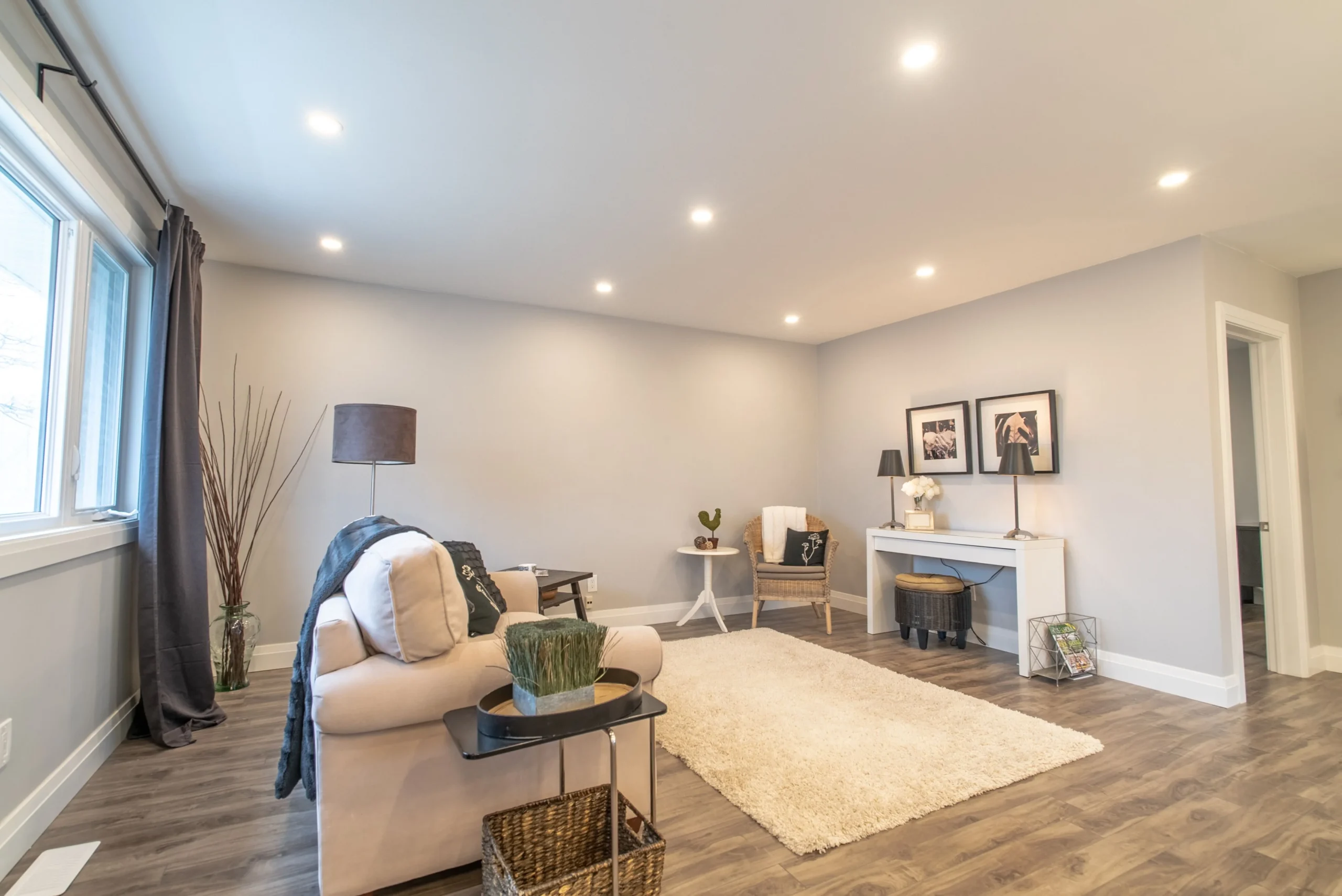 photo minimalist living room with beige sofa area rug side table lamp decor chair wall art and recessed ceiling lights on wood flooring