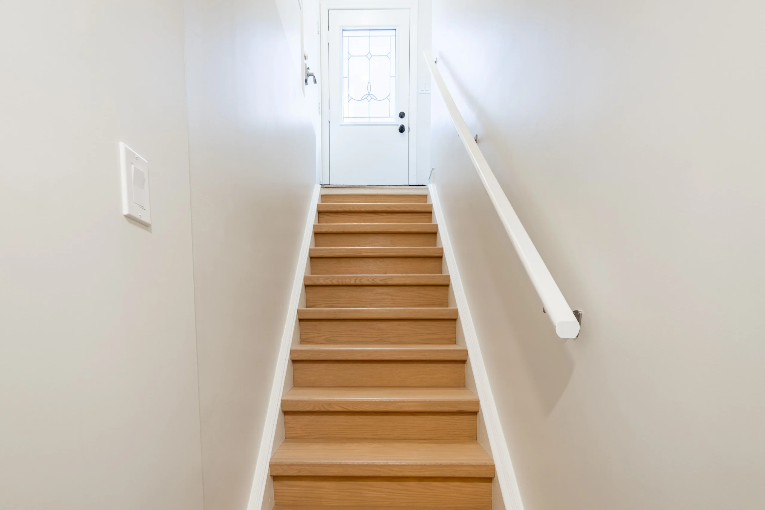 photo-straight-staircase-with-wood-steps-white-walls-and-handrail-leading-up-to-door-with-frosted-glass-panel-at-top