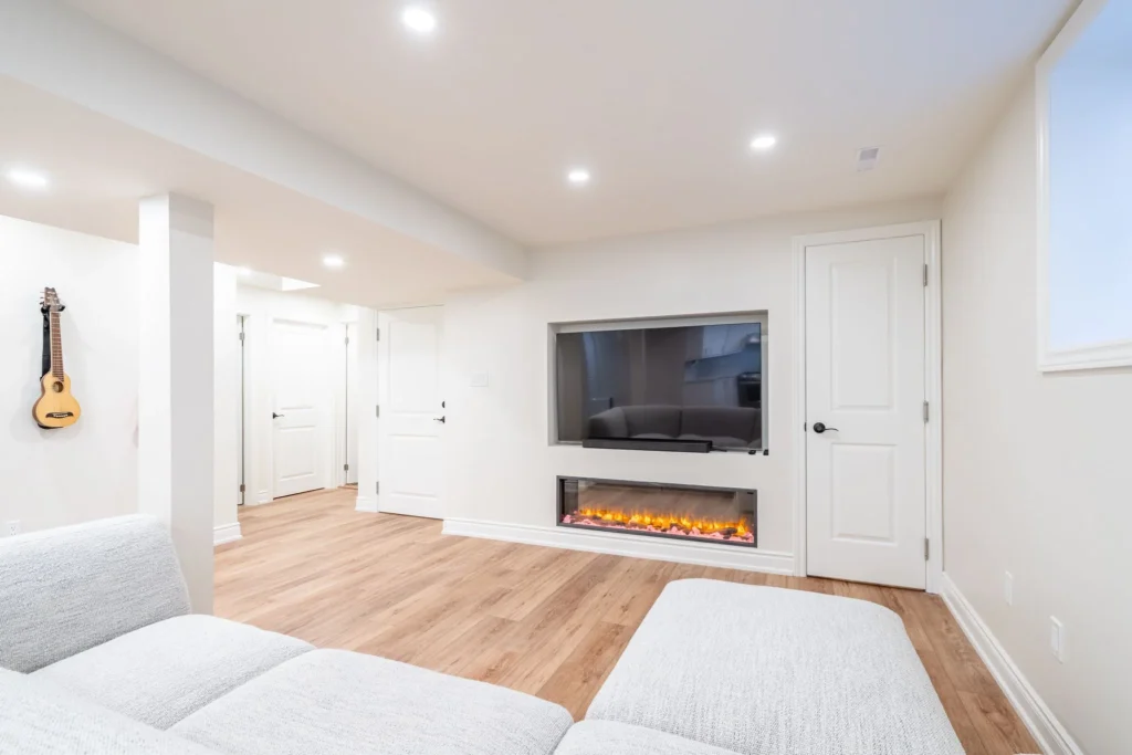 Photo of modern basement living room with sectional sofa, wall mounted television, and electric fireplace feature wall