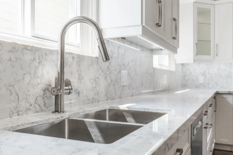 Photo stainless steel faucet over double sink and marble countertop