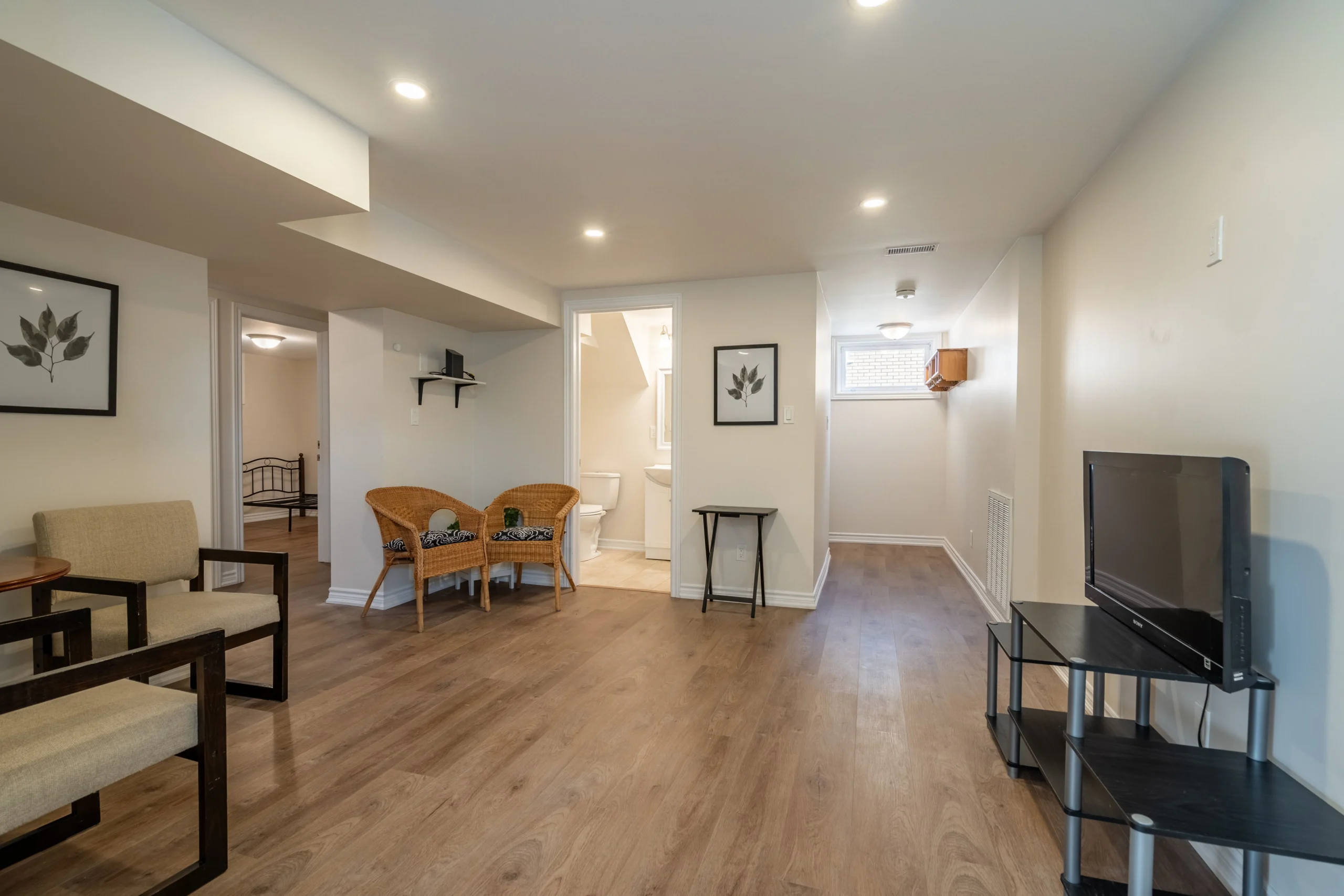 photo finished basement living area with wood flooring chairs tv stand doorways and small window
