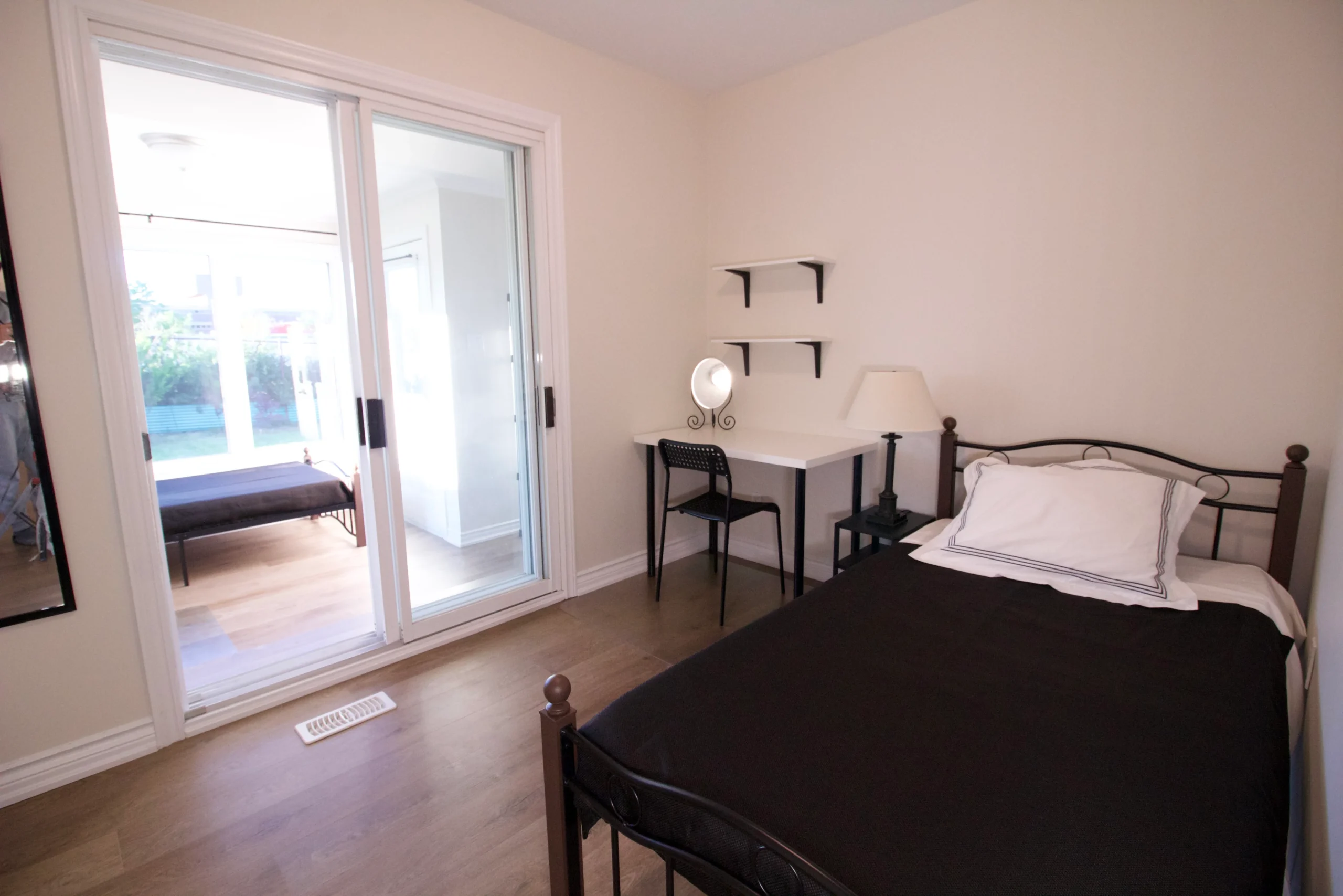 Photo bedroom with black metal bed frame sliding glass door illustrating which room to renovate first