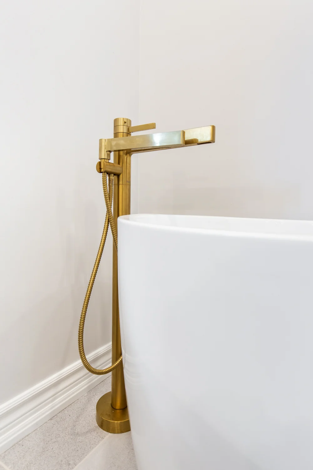 Photo gold bathtub faucet beside white tub for aging in place design