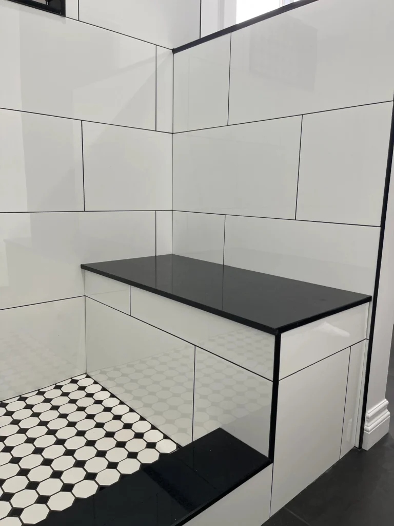 Photo tiled shower bench with black seat and patterned floor for aging in place design