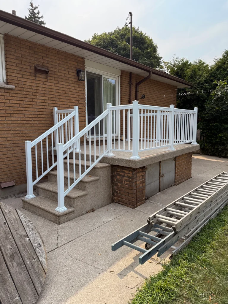photo-backyard-deck-with-white-railing-concrete-steps-brick-house-exterior-and-ladder-on-ground-near-grass-and-patio-area